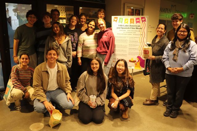 A large group of attendees gathered around the Film Week poster in the foyer
